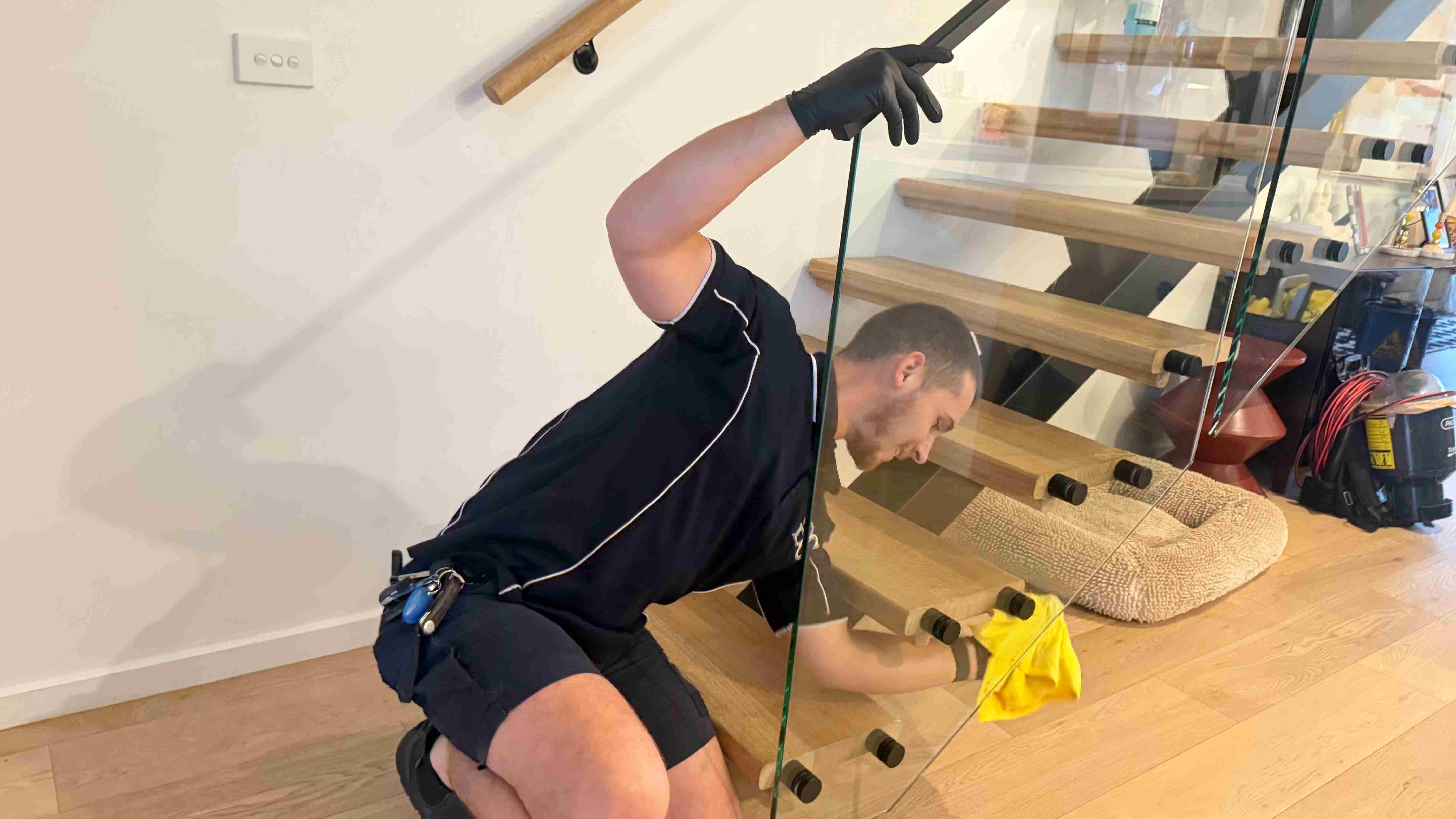 Gleam Clean Co. cleaner polishing a glass staircase balustrade